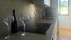 A modern kitchen with a sleek countertop, a wine bottle, and two wine glasses.