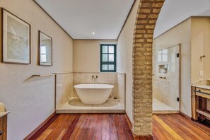 A spacious bathroom with a freestanding bathtub, a window, and a stone archway. - Hotel Borgo Del Vino (Areal)