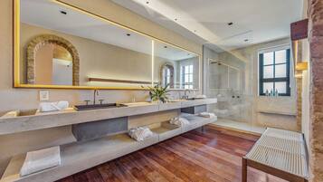 Un baño moderno con un espejo grande, varios lavamanos y suelo de madera.