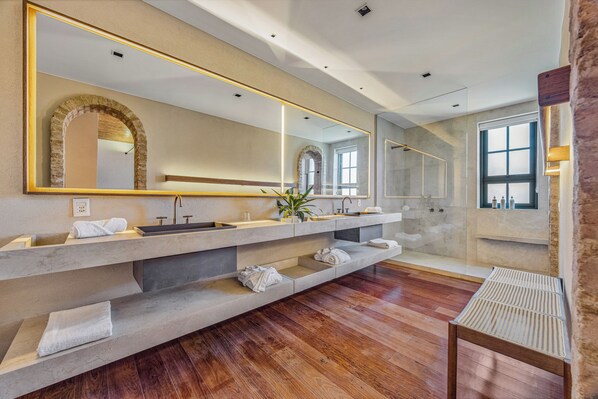 A modern bathroom with a large mirror, multiple sinks, and a wooden floor. - Hotel Borgo Del Vino (Areal)
