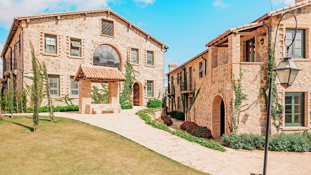 A stone building with a central courtyard, arched doorways, and a tiled roof. - Hotel Borgo Del Vino (Areal)