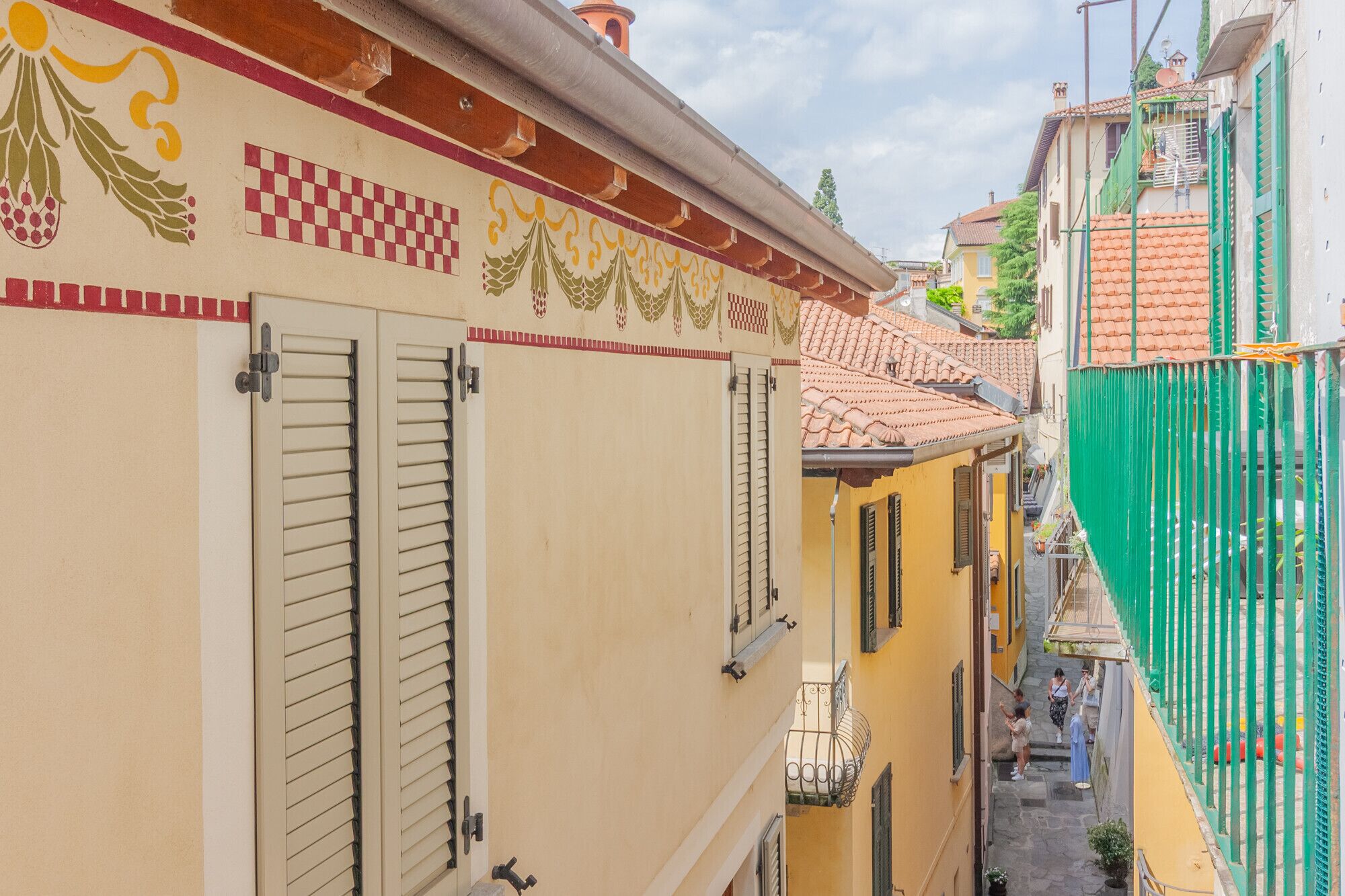 Uma rua estreita com edifícios de arquitetura tradicional, incluindo persianas e detalhes decorativos nas fachadas.