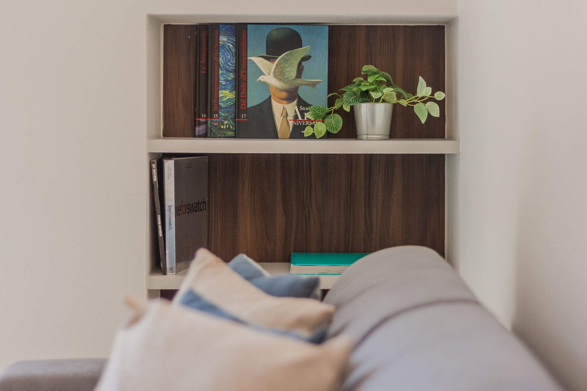 Una estantería con libros, un adorno y una planta en maceta.
