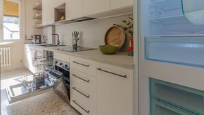 Una cocina moderna con armarios blancos, lavavajillas, horno y refrigerador.
