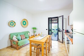 Um espaço compacto com mesa de jantar, sofá verde e área de cozinha.
