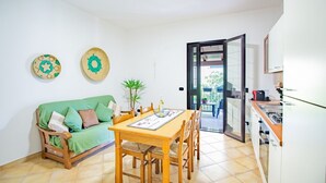 A compact living space with a dining table, a green sofa, and a kitchen area.