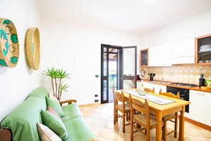 A compact living space with a dining area, kitchenette, and a sliding glass door leading to an outdoor area.