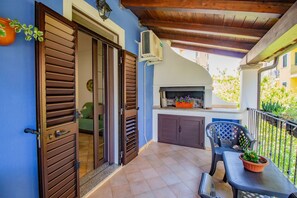 A balcony with a grill, a chair, and a table with a potted plant. - Sa Sterlizia by All4sardinia  (Cardedu)