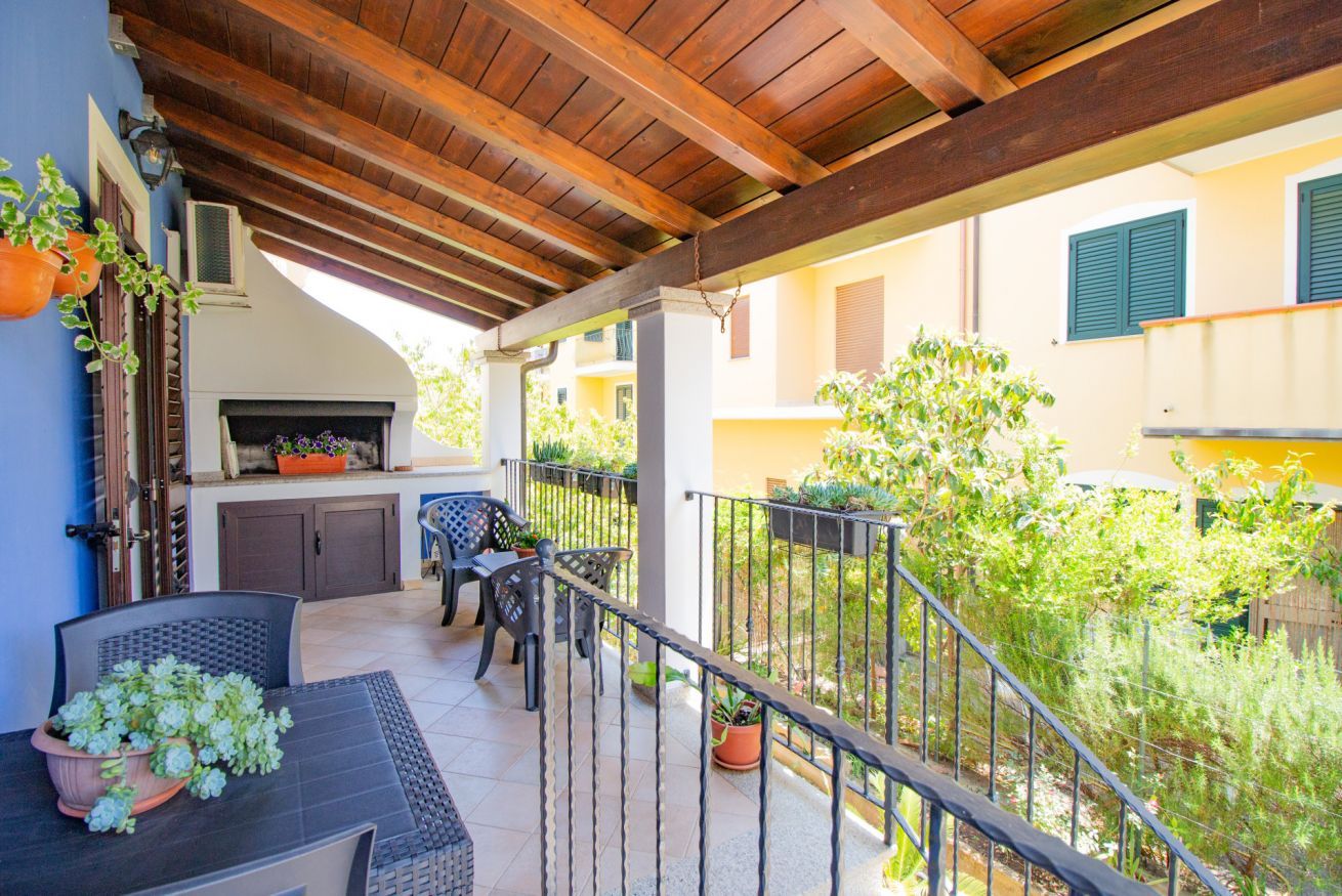 Un patio al aire libre con una pérgola de madera, una parrilla y asientos.