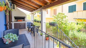 An outdoor patio with a wooden pergola, a grill, and seating.