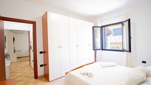 A bedroom with a bed, a wardrobe, and a window with curtains. - Sa Sterlizia by All4sardinia  (Cardedu)