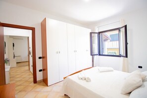 A bedroom with a bed, a wardrobe, and a window with curtains. - Sa Sterlizia by All4sardinia  (Cardedu)
