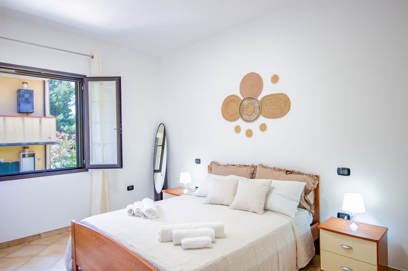 A bedroom with a bed, bedside tables, a window, and a wall decoration.