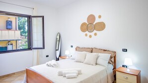 A bedroom with a bed, bedside tables, a window, and a wall decoration.