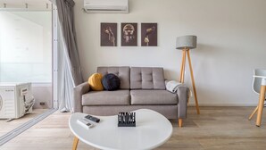Un salon moderne avec un canapé gris, une table basse blanche et un lampadaire.