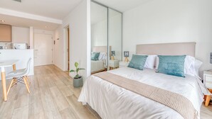 Une chambre moderne avec un grand lit, des tables de chevet, un miroir et un coin bureau avec une chaise.