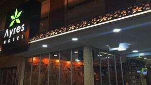 Az Ayres Motel külső megjelenése: feltűnő zöld logó, nagy üvegablakok és csempézett bejárati rész.