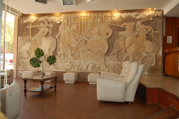 A lobby with a large wall mural, seating area, and a reception desk.