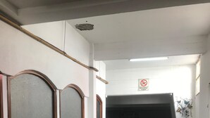 Egy folyosó, amelyen „dohányozni tilos” tábla található, egy cserépben lévő növény és egy ajtó a végén.