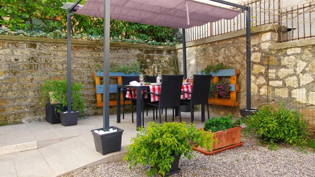 An outdoor patio with tables and chairs, a pergola with a canopy, and potted plants. - Charming tourist apartment near historic center of Montepulciano. Holiday home. (Montepulciano)