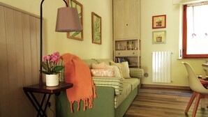 A cozy living room with a green sofa, a small table with a lamp, and a potted plant. - Charming tourist apartment near historic center of Montepulciano. Holiday home. (Montepulciano)