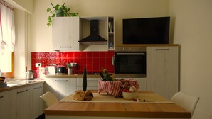 A kitchen with a wooden table, white cabinets, a red tiled backsplash, a black range hood, and a large oven. - Charming tourist apartment near historic center of Montepulciano. Holiday home. (Montepulciano)