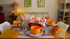 A cozy dining area with a table set for breakfast, including a coffee pot, orange cups, a croissant, and a checkered cloth. - Charming tourist apartment near historic center of Montepulciano. Holiday home. (Montepulciano)