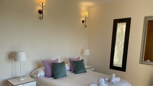 A hotel room with a large bed, two bedside tables with lamps, a mirror, and a window with curtains. - Villa Horizon Salobre 7 (San Bartolomé de Tirajana)