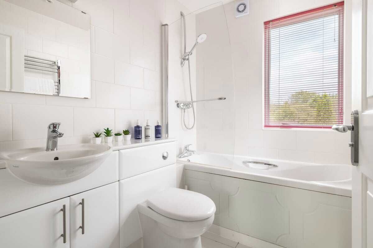 Un baño moderno con lavamanos, inodoro y bañera blancos.