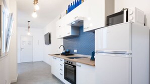 A modern kitchen with white cabinets, a wooden countertop, a built-in oven, a microwave, and a sink. - Océano: Acogedor y Luminoso Apartamento (Santa Cruz de Tenerife)