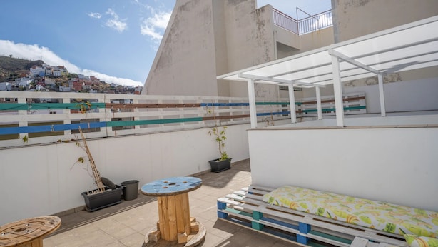 A rooftop terrace with a white pergola, a wooden table, a bench, and potted plants. - Océano: Acogedor y Luminoso Apartamento (Santa Cruz de Tenerife)