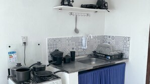 A compact kitchen with a gas stove, a sink, and a dish rack. - Casas Astro Rei (Cairu)
