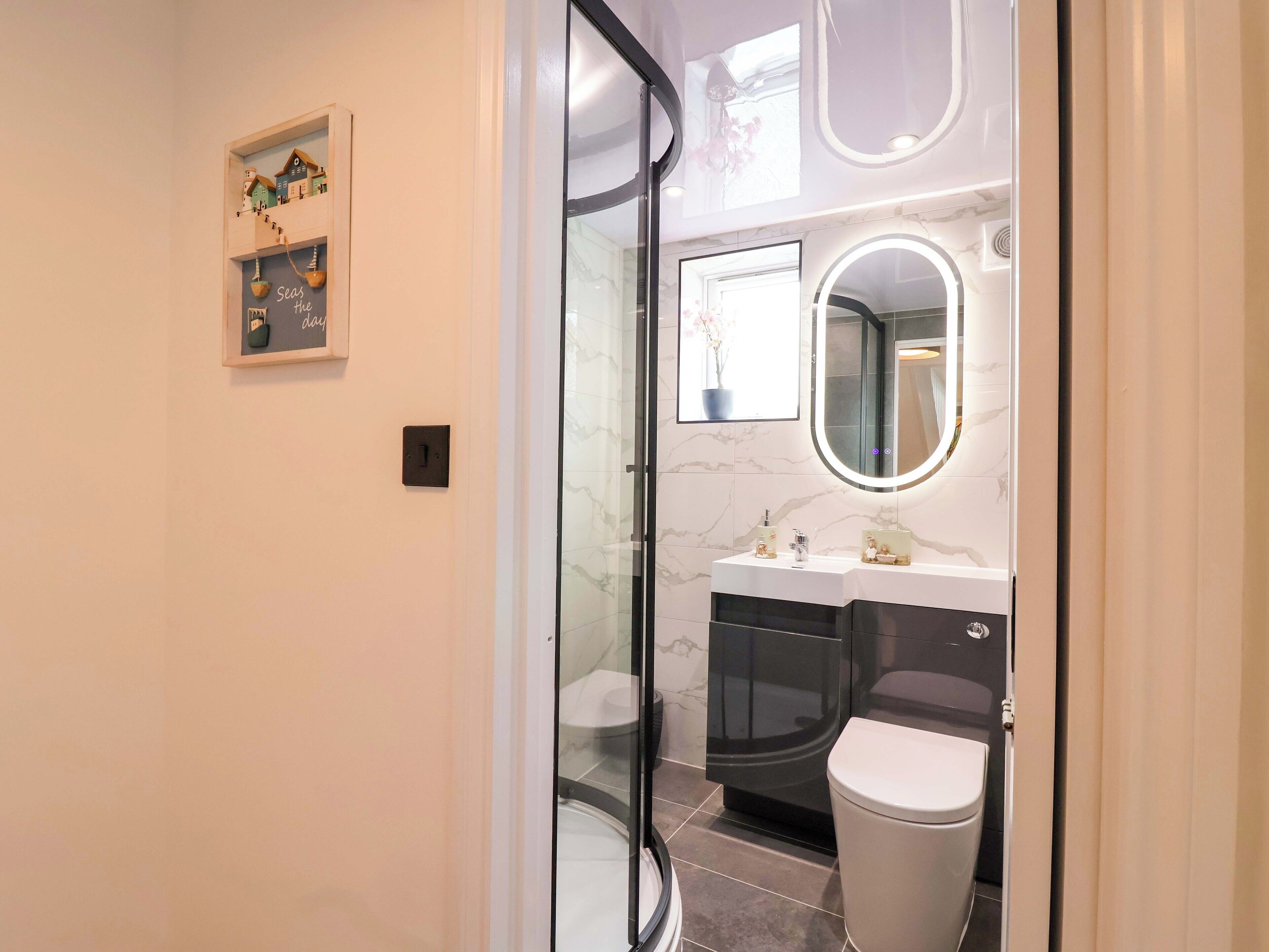 A modern bathroom with a glass shower enclosure, a vanity with a marble countertop, and a toilet.
