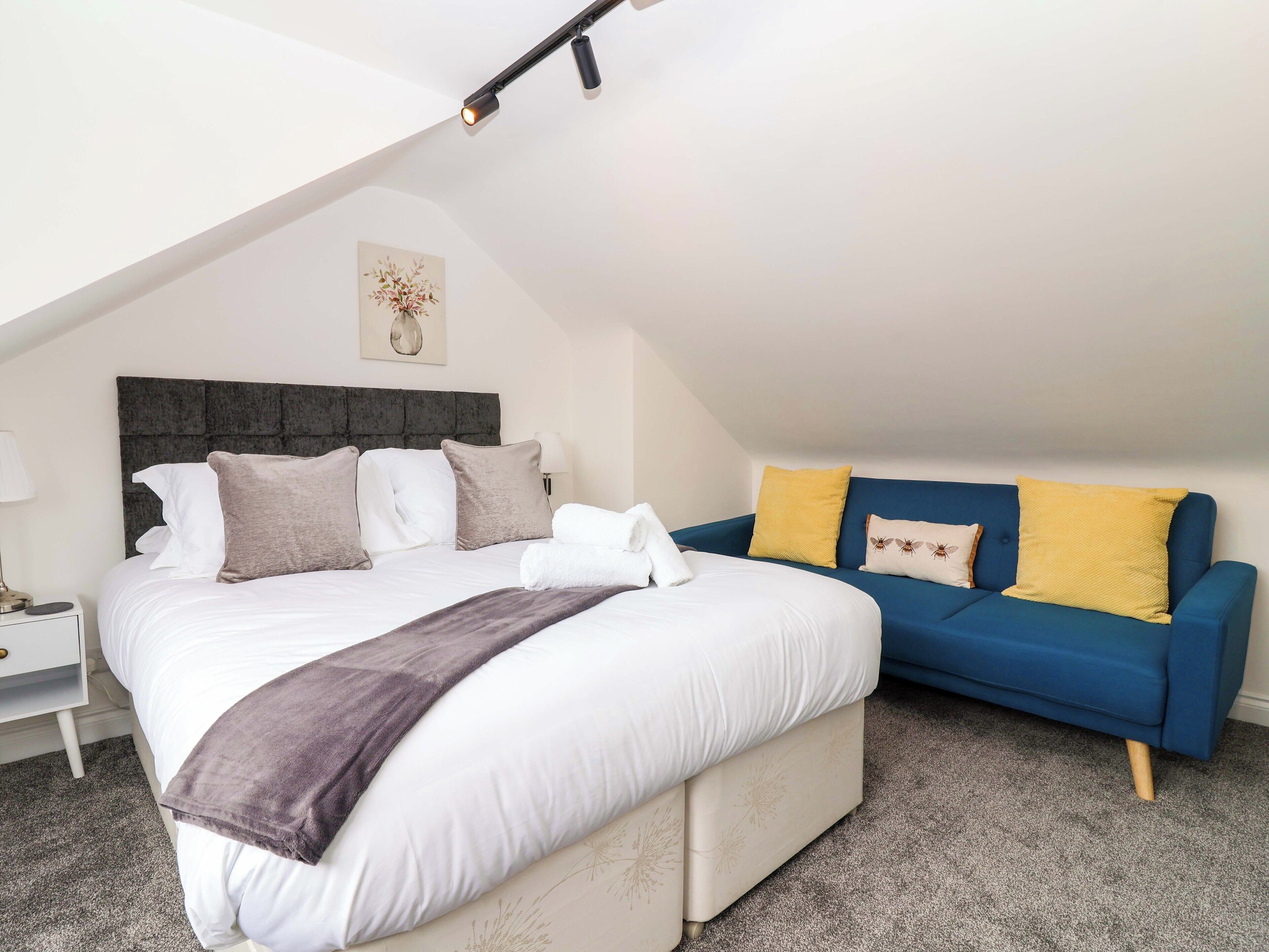 Une chambre à coucher avec un lit, un canapé bleu, une table de chevet et une lampe.