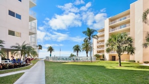 A hotel with a pool, palm trees, and a clear sky. - Updated Condo with Beach Access! Shared Pools, BBQ Area! Jamaica Royale Unit 053 (Siesta Key)
