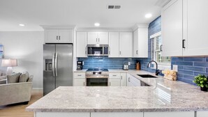 A modern kitchen with white cabinets, a stainless steel refrigerator, a microwave, and a sink. - Updated Condo with Beach Access! Shared Pools, BBQ Area! Jamaica Royale Unit 053 (Siesta Key)