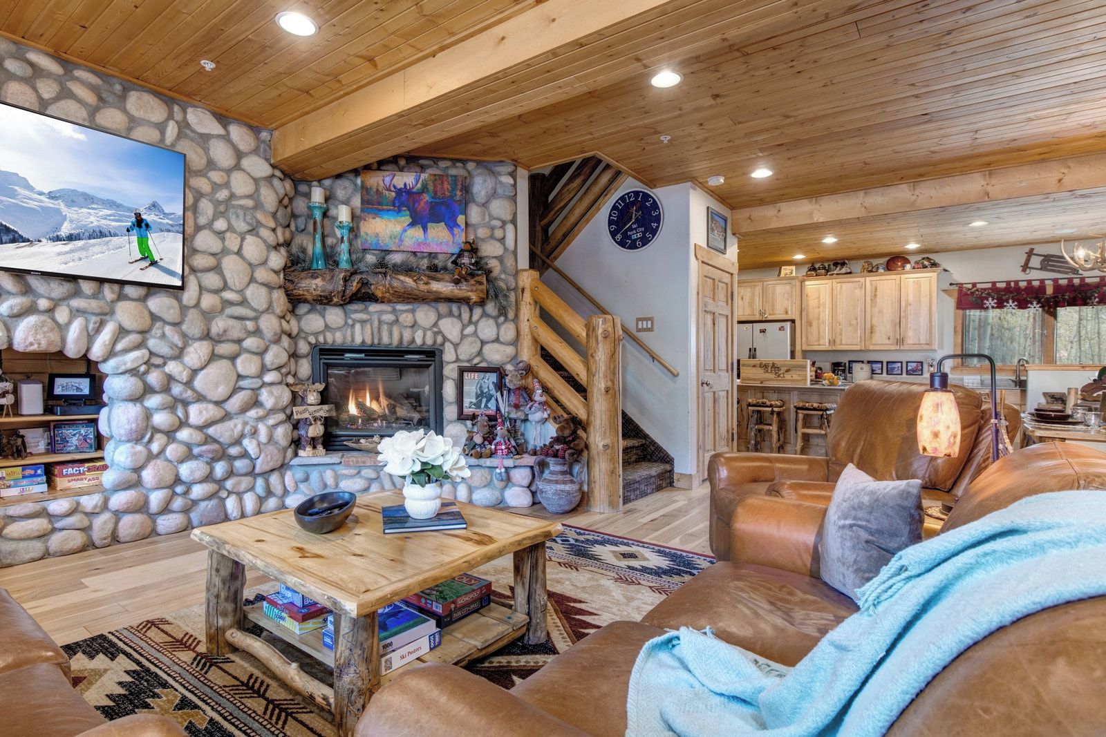 A cozy interior with a stone fireplace, wooden ceiling, and a stone wall.