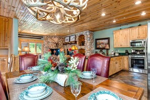A dining area with a stone wall, wooden ceiling, and a chandelier. - Timber Wolf Lodge | KBM Resorts | Gas Fireplace, Common Hot Tubs, Near Canyons Village | 2 Units, 5 Bedrooms | ML-1343 (Park City)
