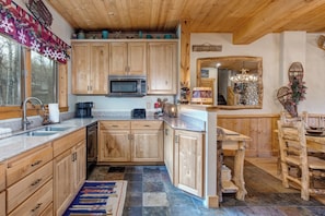 A kitchen with wooden cabinets, a microwave, a sink, and a dining area with a wooden table and chairs.