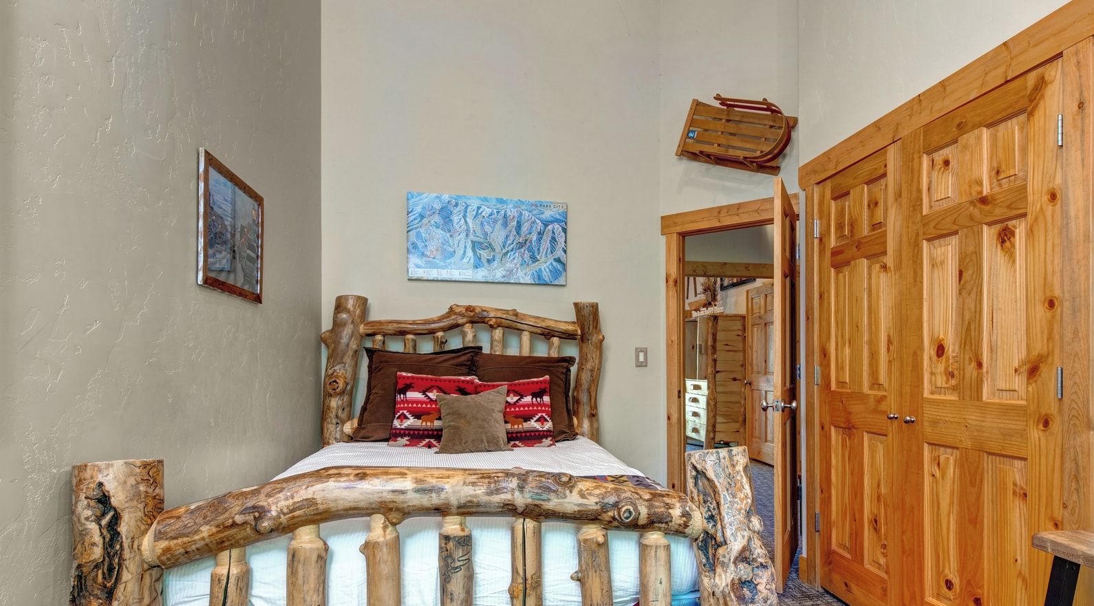 Une chambre à coucher rustique avec un lit en bois, une porte en bois et un tableau accroché au mur.