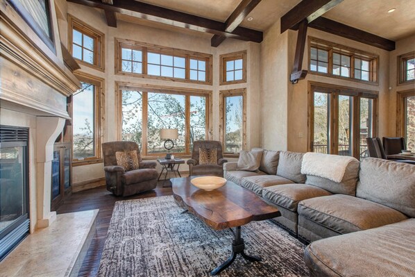 A spacious living room with a fireplace, large windows, and a cozy seating area.
