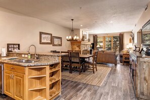Une cuisine spacieuse dotée de plans de travail en granit, d’armoires en bois et d’un coin repas avec une grande table et des chaises.