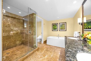 Un baño moderno con ducha de vidrio, una bañera blanca y un tocador de mármol.