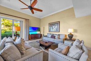 A living room with a television, sofa, coffee table, and a ceiling fan. - Honua Kai | Ocean View 4 BR, Sleeps 14 | Car Incl. w/ 6+ Nights | HKH ML-1351 by KBM (Lahaina)