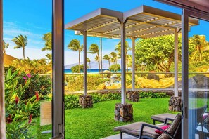 A covered outdoor area with a view of a beach and palm trees.