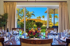 A dining table set for six with a view of palm trees and a building.