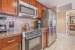 A kitchen with a Bosch microwave, stainless steel refrigerator, and a gas stove.