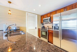 Une cuisine équipée d’appareils électroménagers en acier inoxydable, d’un plan de travail en granit et d’armoires en bois.