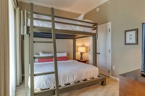 Una camera con un letto a castello, una scala in legno, una lampada da comodino e una porta.