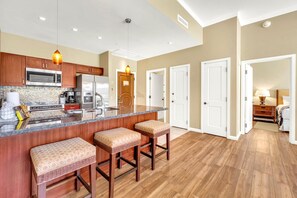 Una cocina moderna con una isla central, taburetes de bar y un comedor con lámpara.